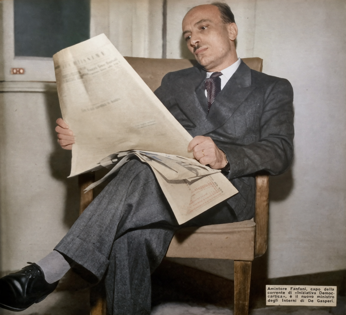 Amintore Fanfani legge un giornale seduto, ritratto fotografico del 1953 colorizzato, nuovo ministro degli Interni nel governo De Gasperi